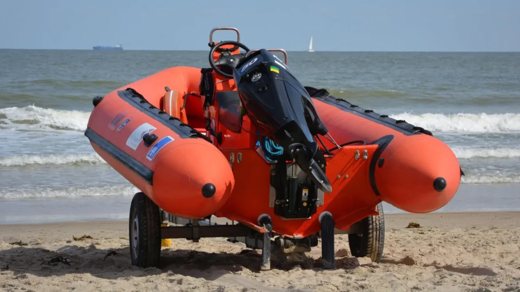Embarcación semirrígida naranja con motor fueraborda en la playa